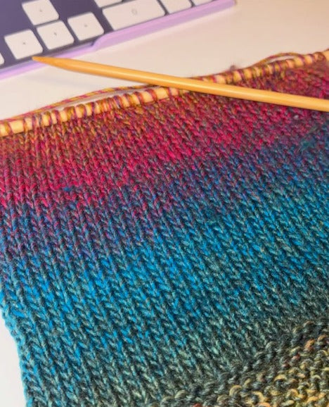 Close-up of stockinette stitches in gradient yarn on a bamboo needle